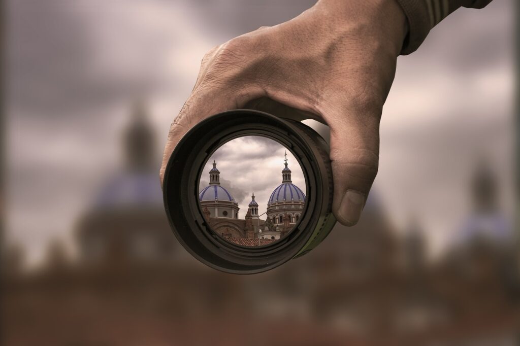 Hand focusing a camera lens, symbolizing scope determination for plastic packaging tax in Spain